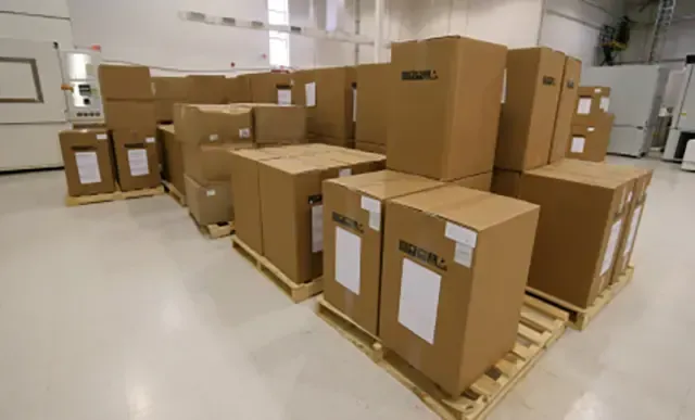 A warehouse filled with lots of cardboard boxes on wooden pallets