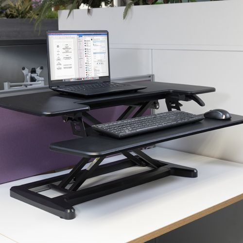 a laptop computer is sitting on top of a standing desk with a keyboard and mouse .