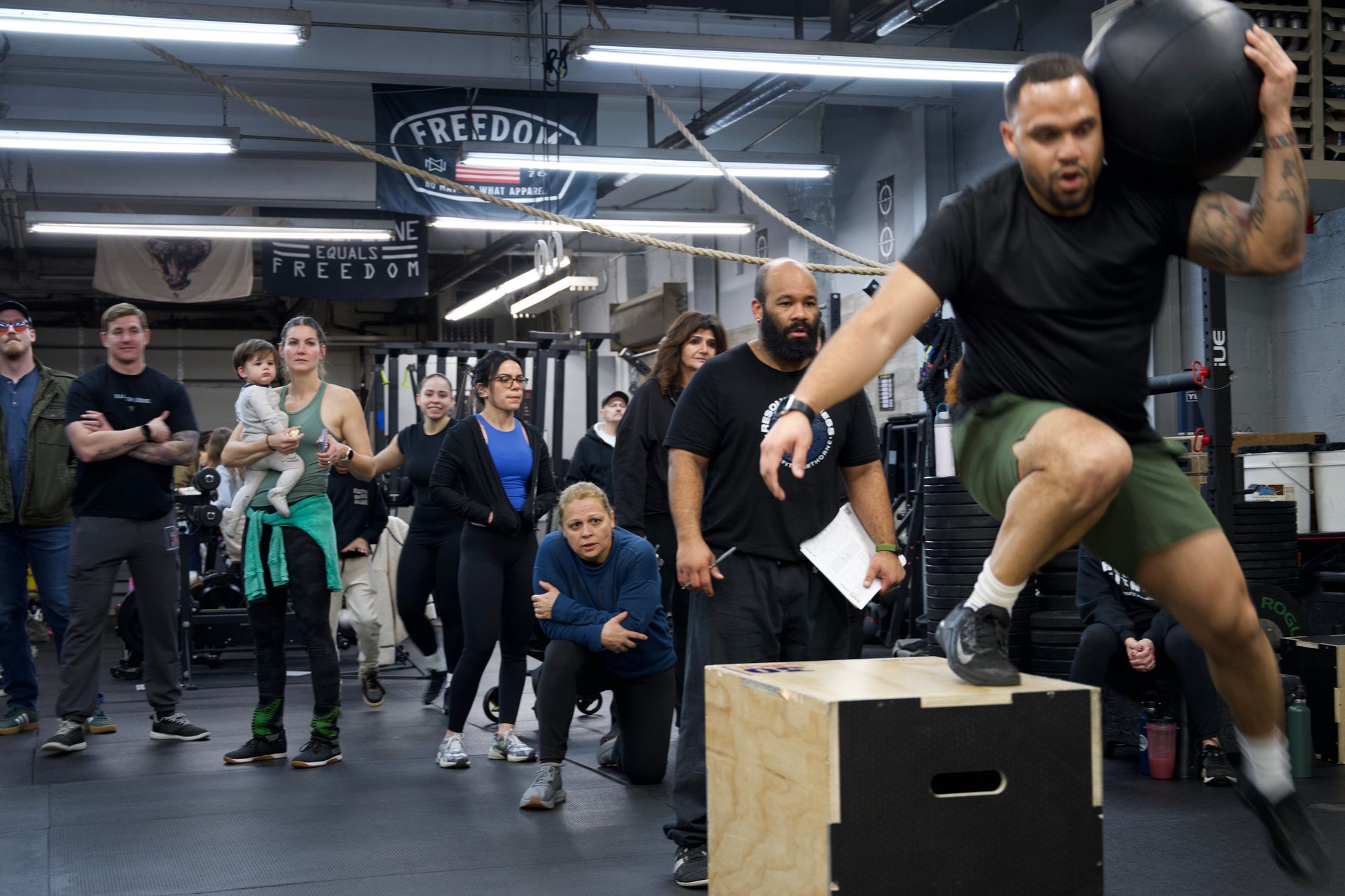 People lifting barbells overhead in a CrossFit gym during a workout class