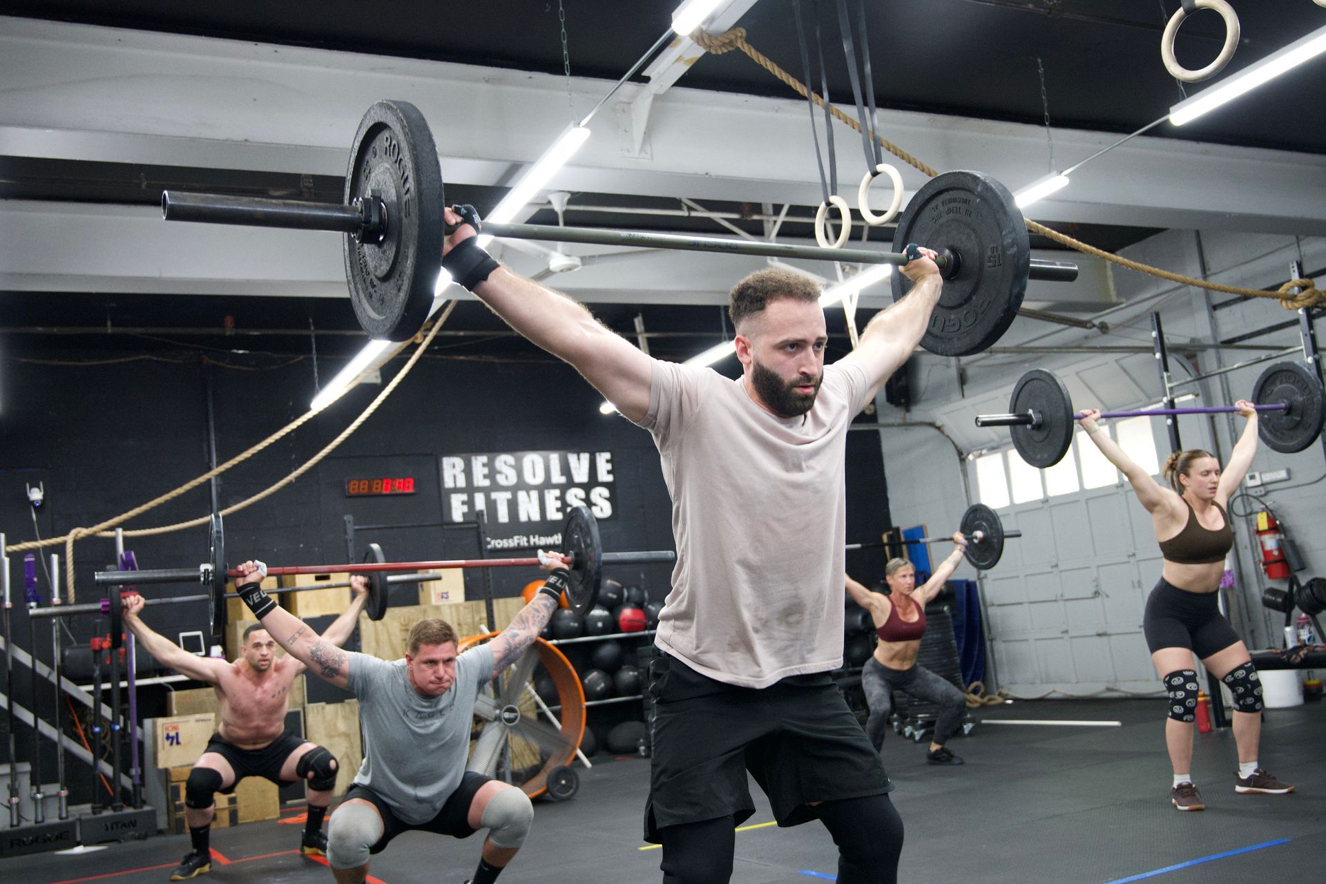 People doing barbell overhead presses in a gym workout class