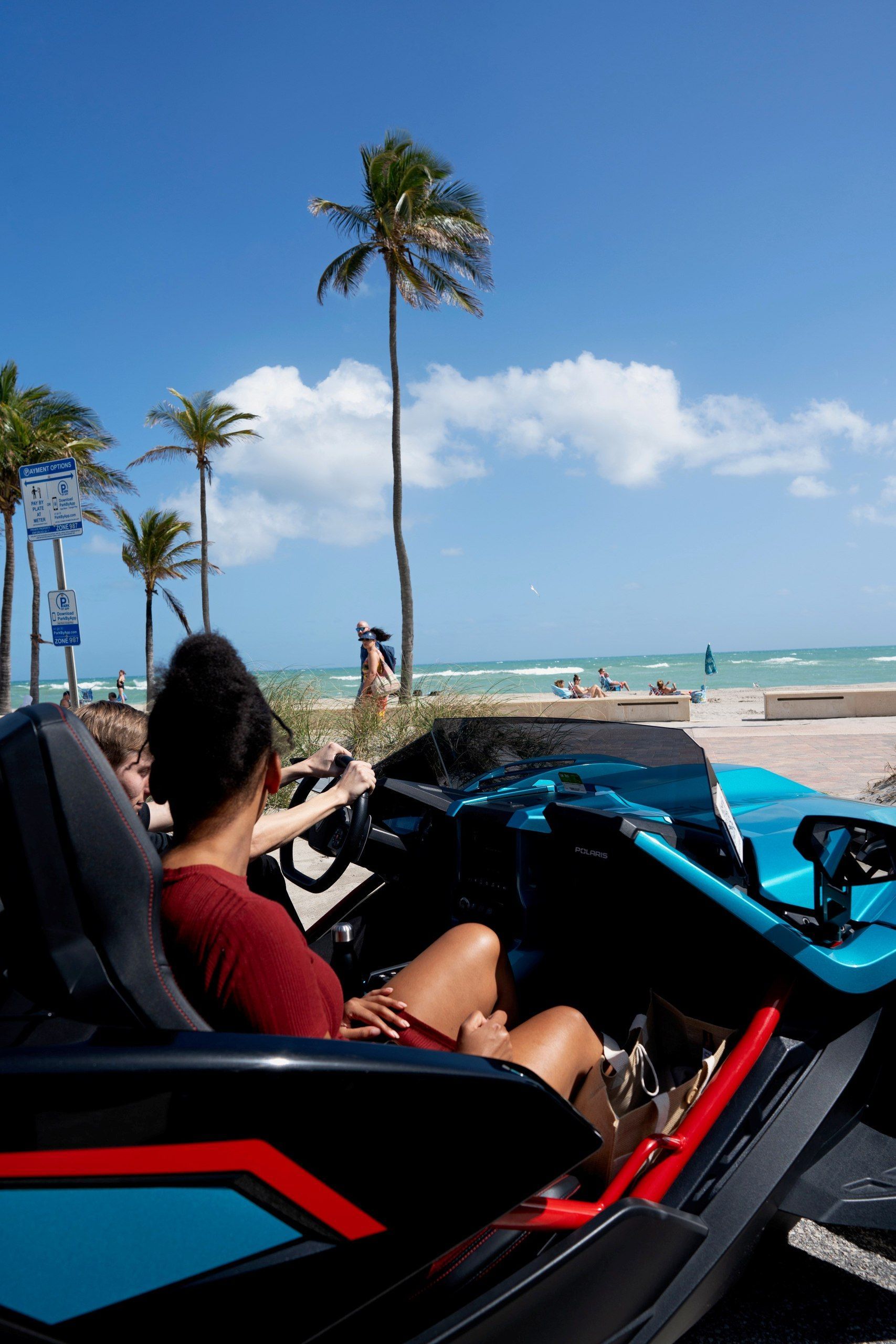 A blue slingshot is parked in front of a building.