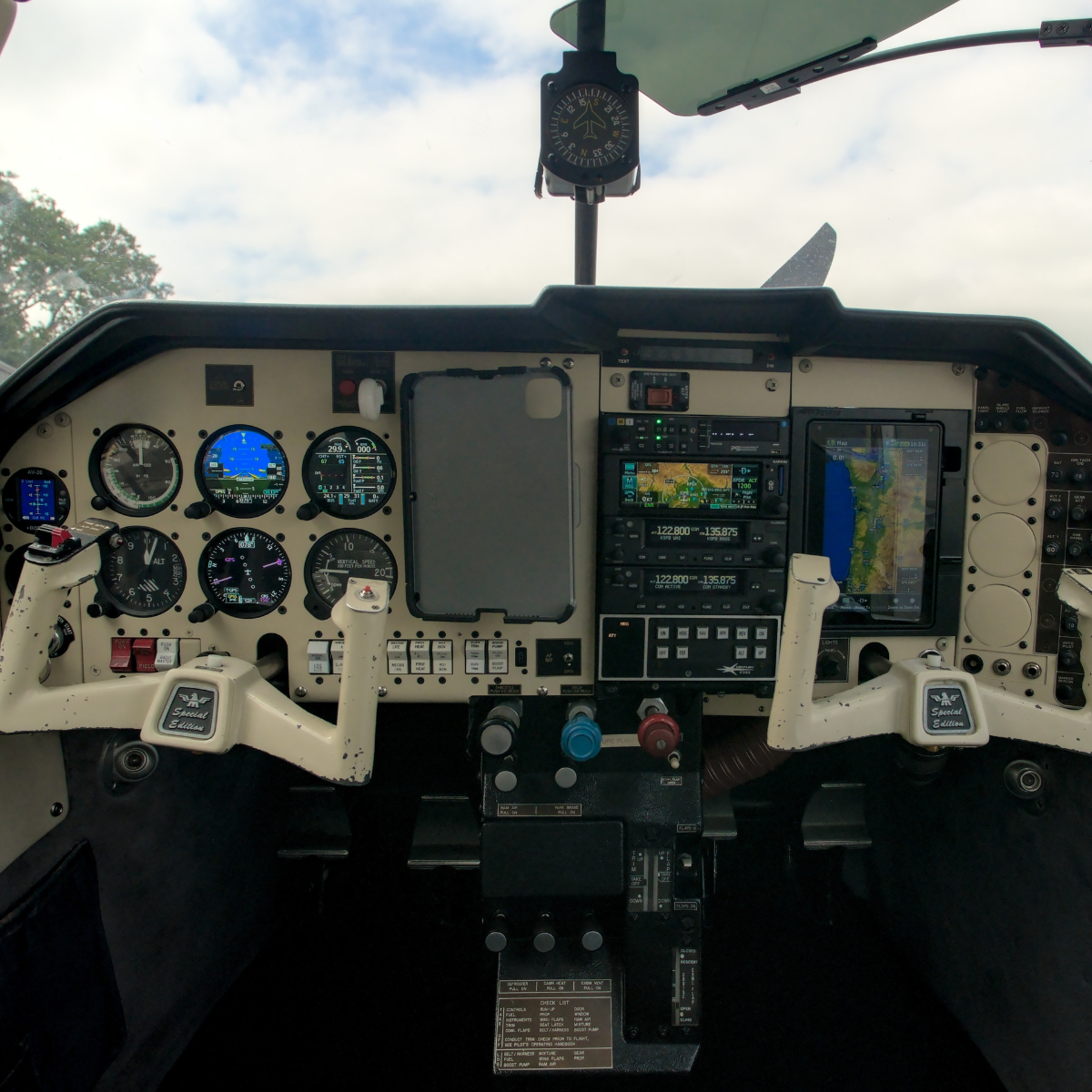 Airplane cockpit interior with instrument panel, control yokes, and navigation screens.