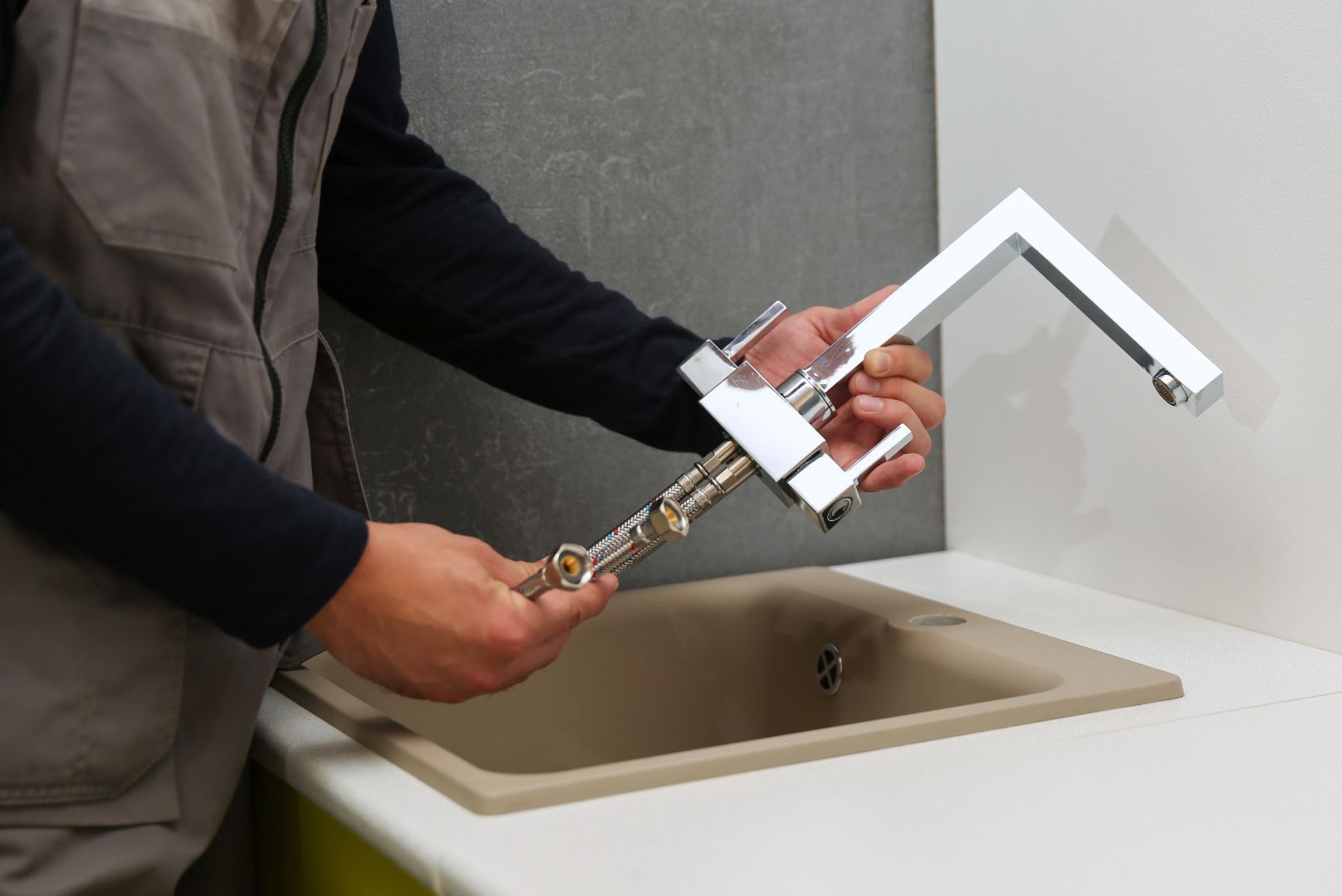 A man is fixing a sink faucet with a wrench.