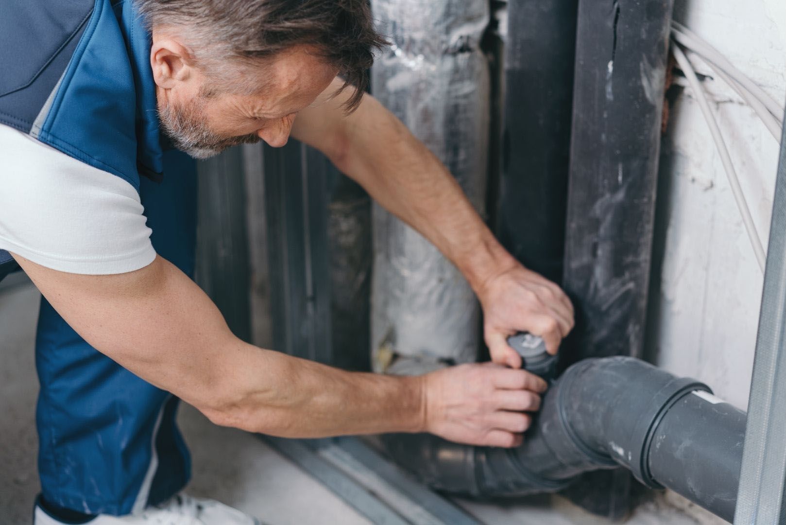 A man is fixing a pipe with a wrench.