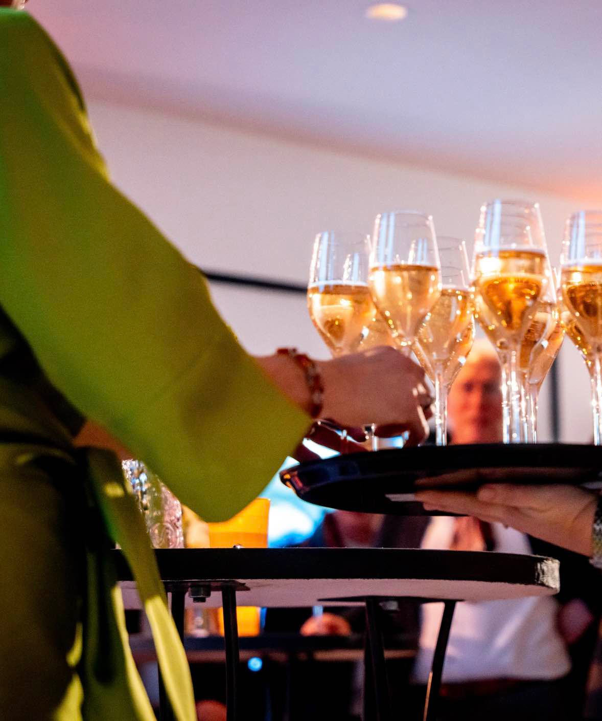 Gast pakt een glas champagne van het dienblad tijdens een zakelijke nieuwjaarsborrel