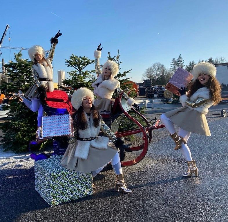 dames in kerstoutfit voor kerstborrel en kerstboom op achtergrond