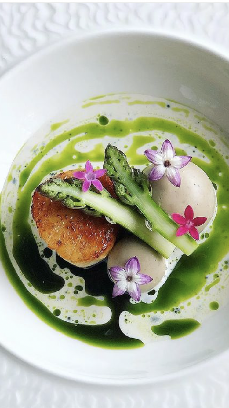 coquilles met groene asperger, eetbare bloemen en basilicum olie