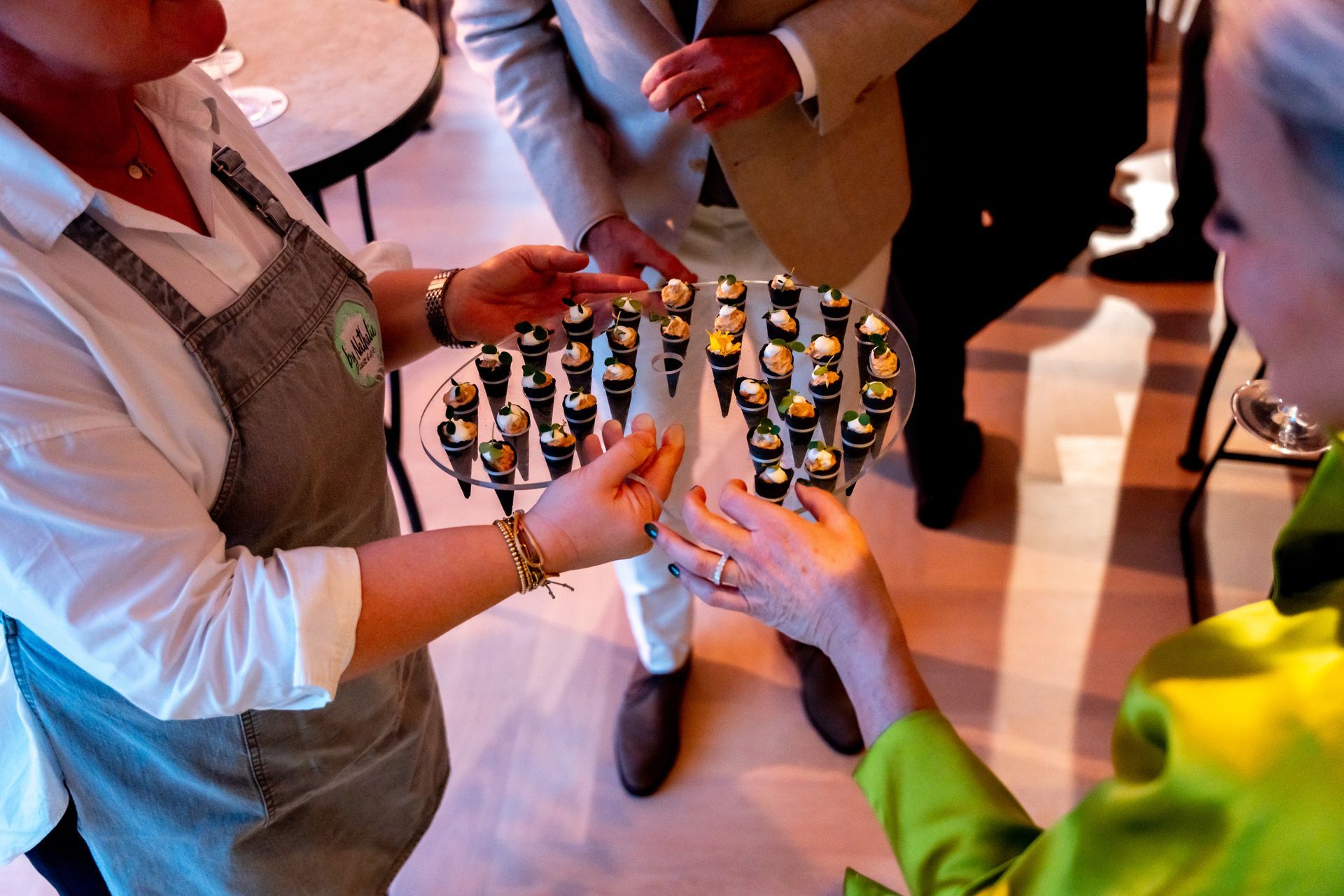 Medewerker serveert amuses op een dienblad aan gasten tijdens een zakelijke borrel