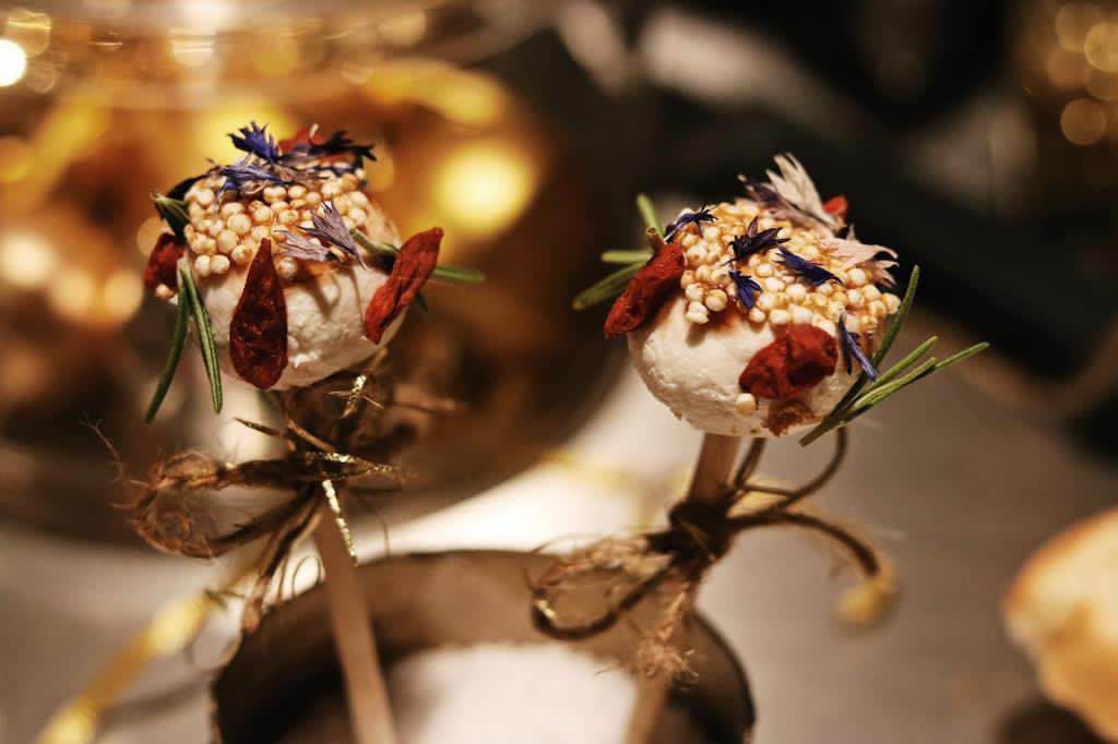 Amuse-lollys met gepofte quinoa, tomaat, rozemarijn en eetbare bloemen op een stokje