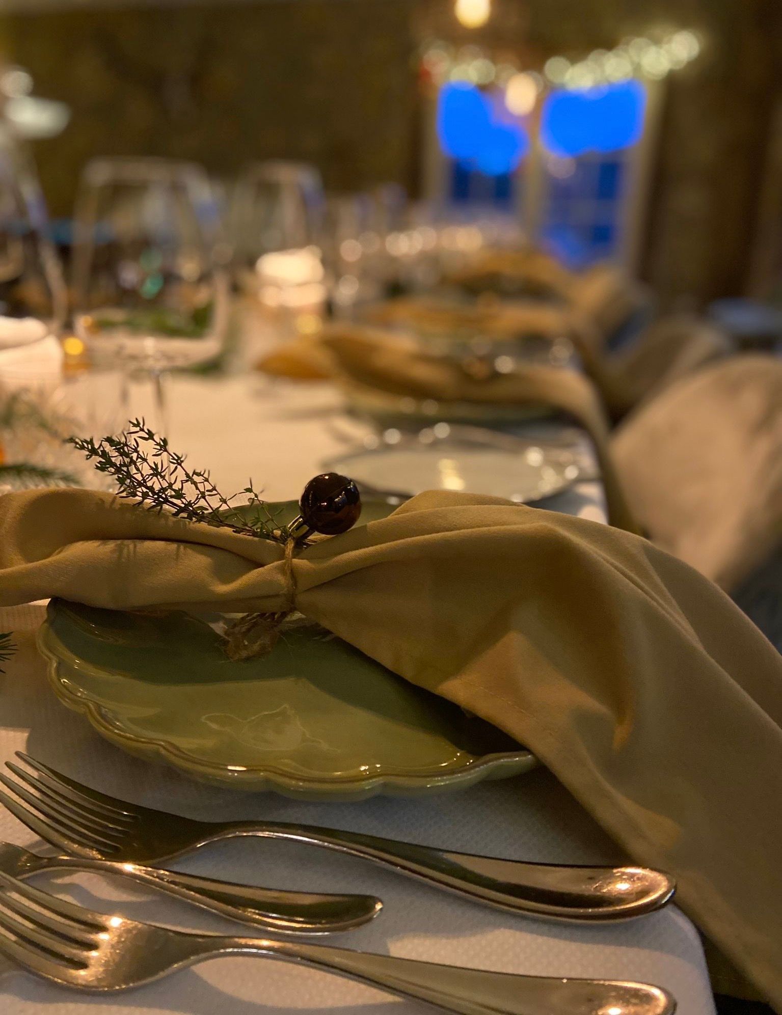 Gedekte tafel met servet, tijmtakje en kerstbal als tafeldecoratie tijdens een kerstdiner