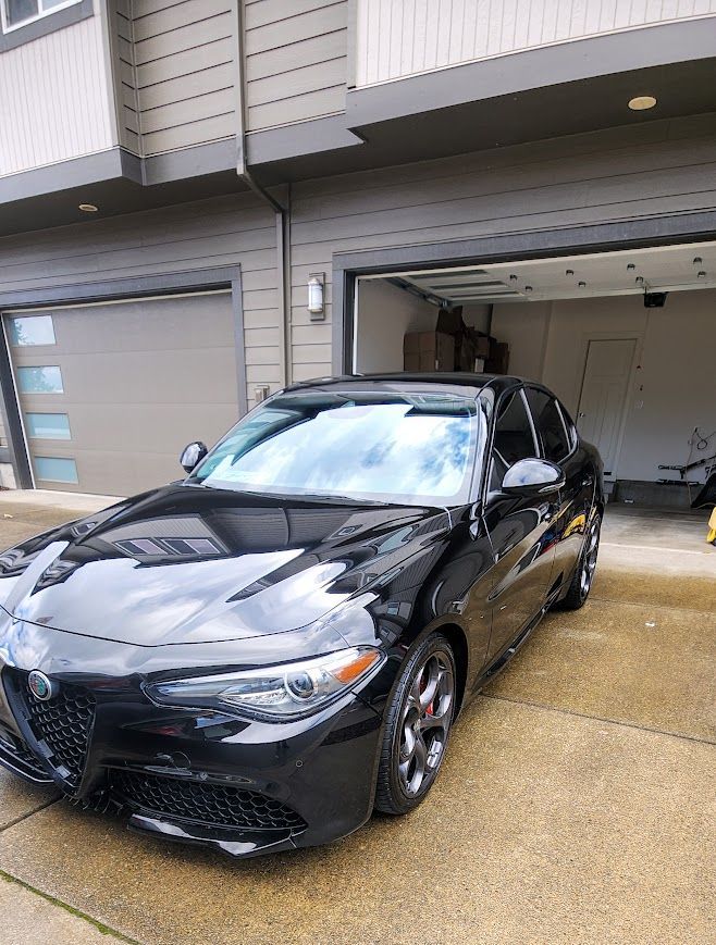A black car is parked in front of a garage.