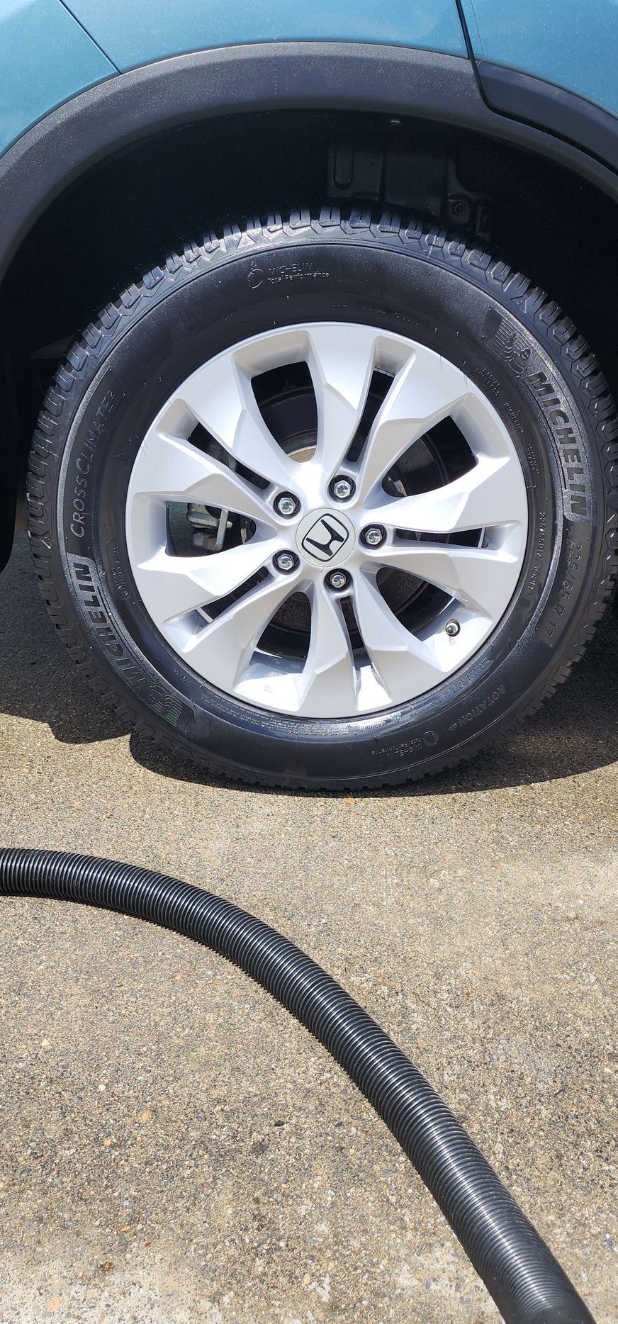 A close up of a tire on a car next to a hose.
