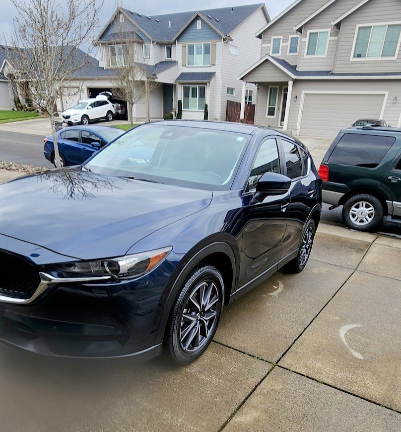 A blue car is parked in front of a house