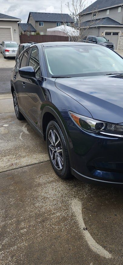 A blue car is parked in a driveway in front of a house.