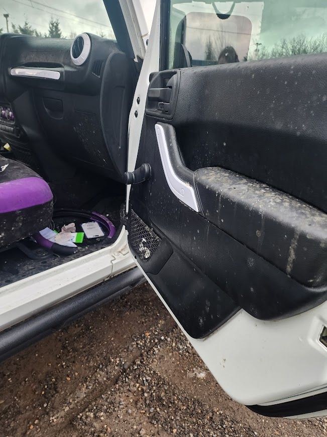 A white jeep with a purple seat is parked in the dirt.