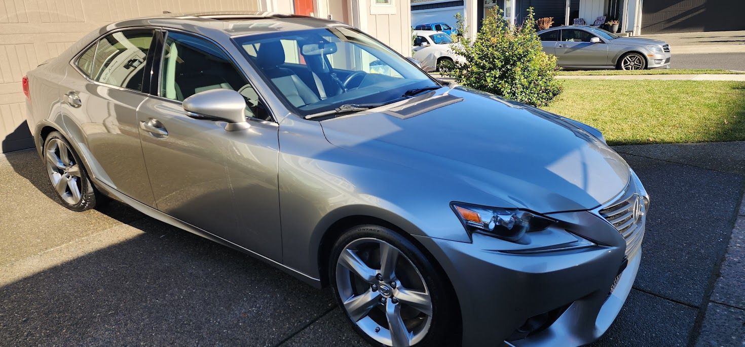 A gray car is parked in a driveway next to a garage.