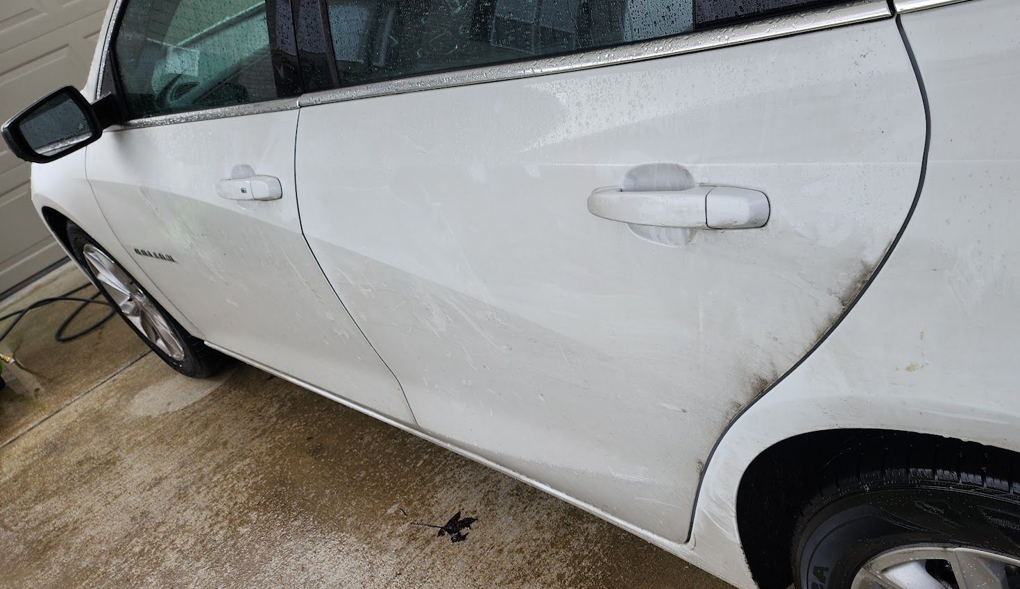 A white car is parked in a driveway next to a garage.