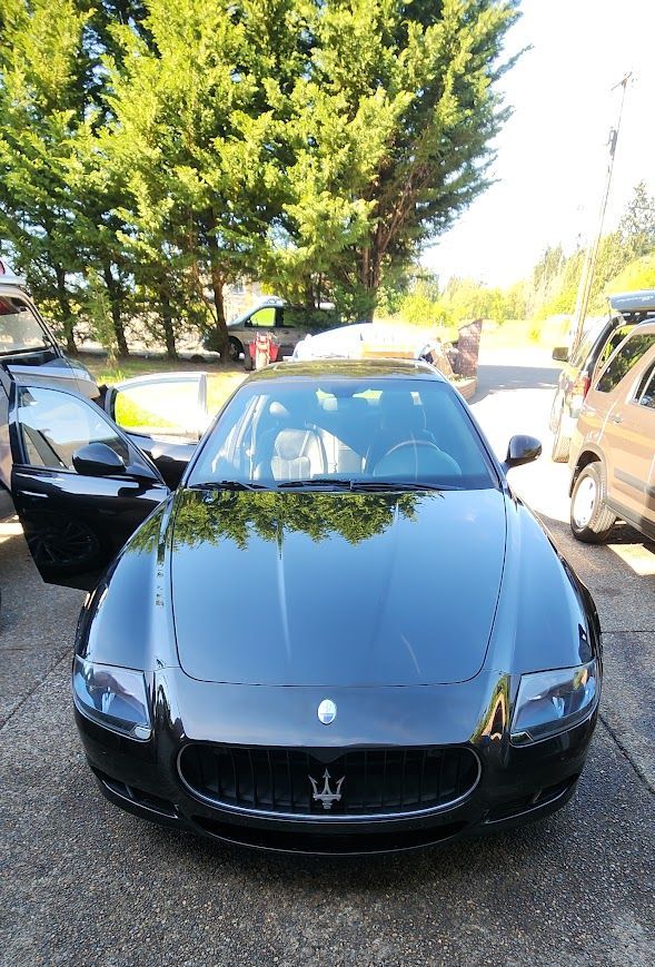 A black maserati car is parked in a parking lot.
