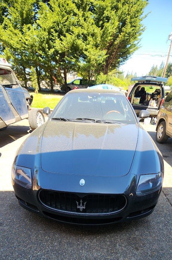A black maserati sports car is parked in a parking lot.