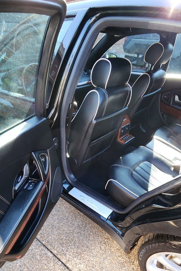 The back seat of a black car with the door open.