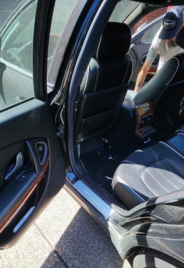 A man is cleaning the interior of a car with a vacuum cleaner.