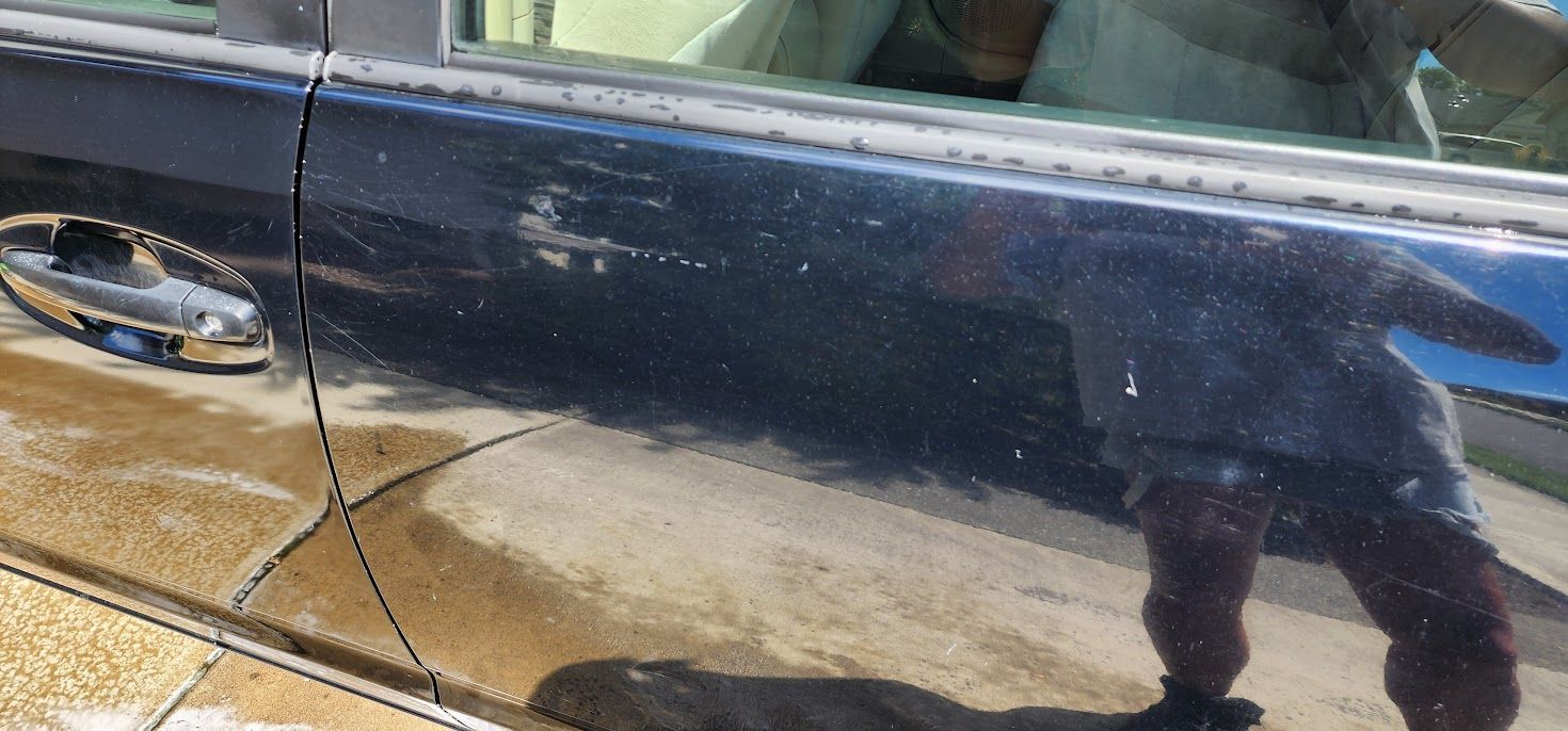 A close up of a car door with a reflection of a person in the window.