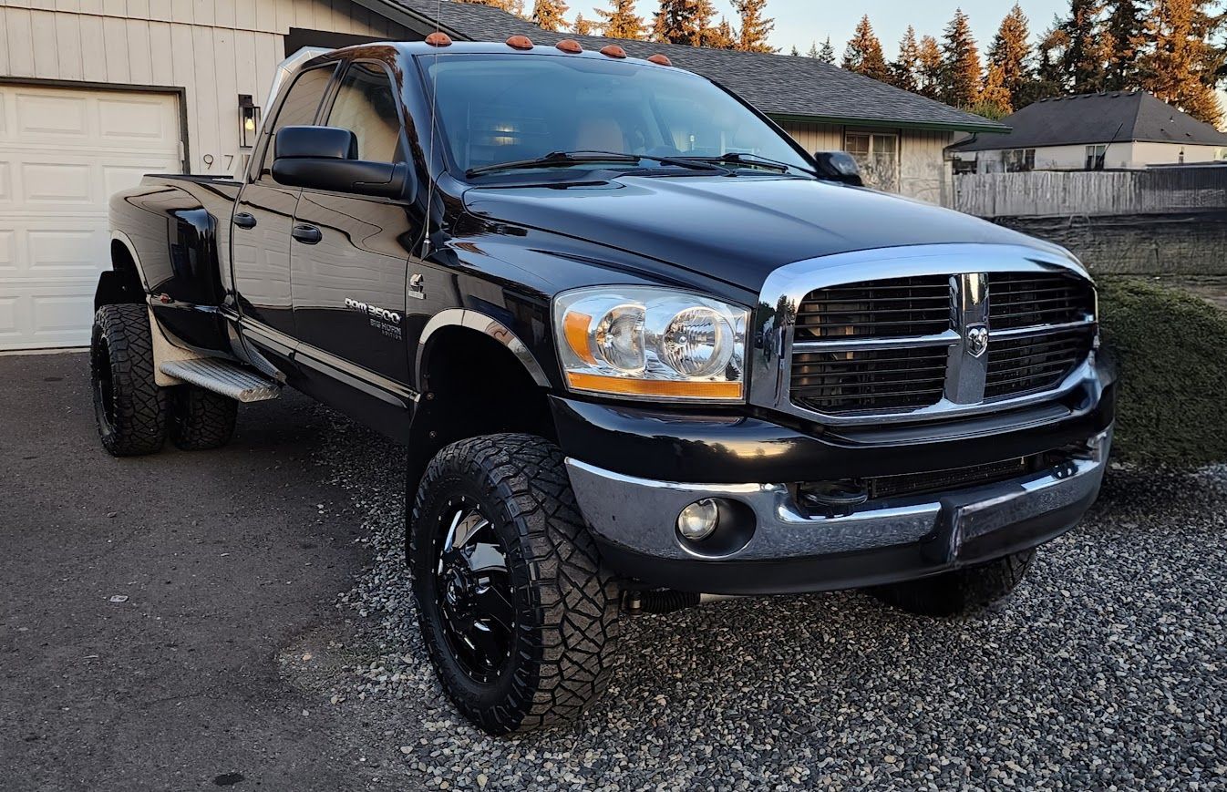 A black dodge ram truck is parked in front of a garage door.