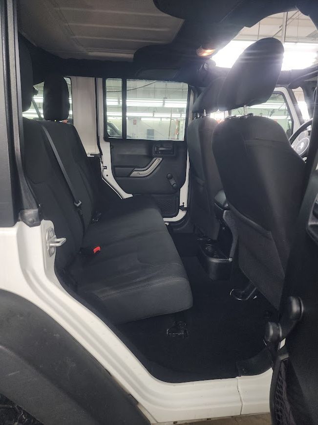 The inside of a white jeep with black seats.