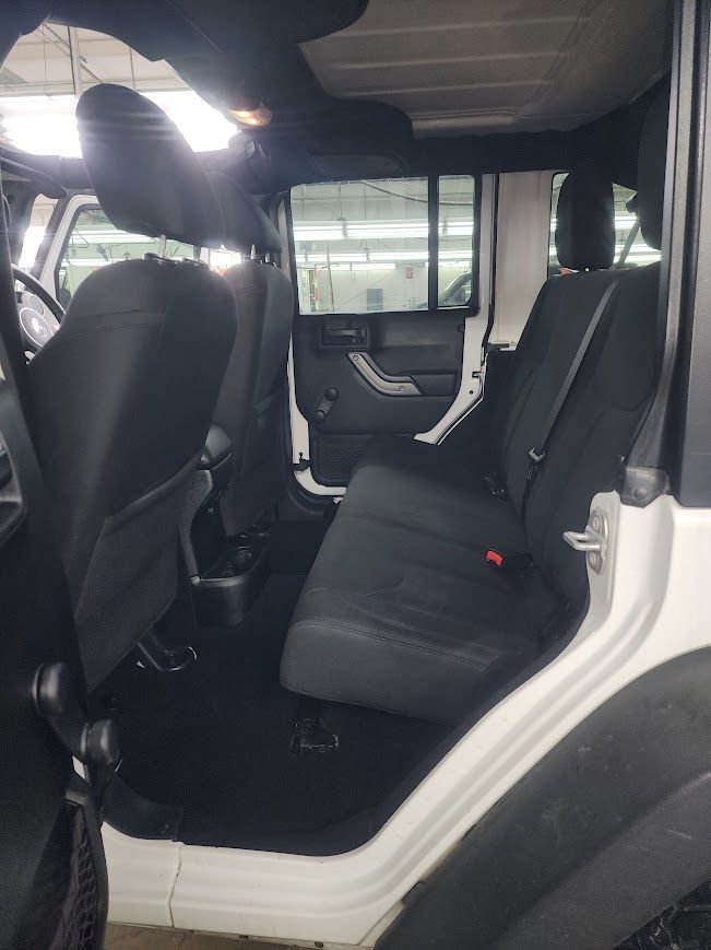 The back seat of a white jeep wrangler with black seats.