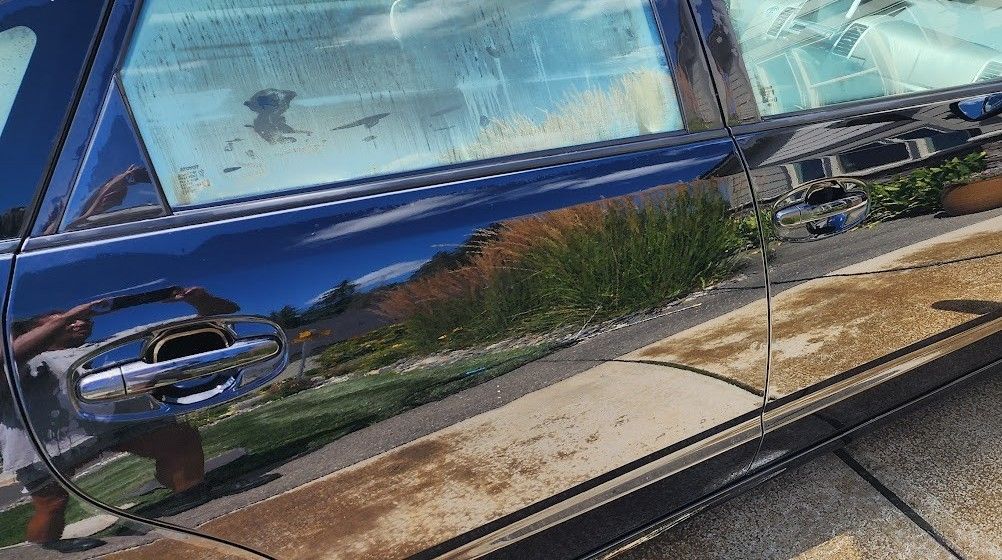A blue car is parked on the side of the road.