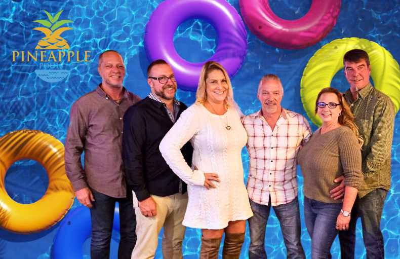 A group of people are posing for a picture in front of a swimming pool.