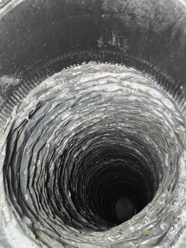 Inside view of a narrow, spiral-textured metal pipe or tunnel leading into darkness