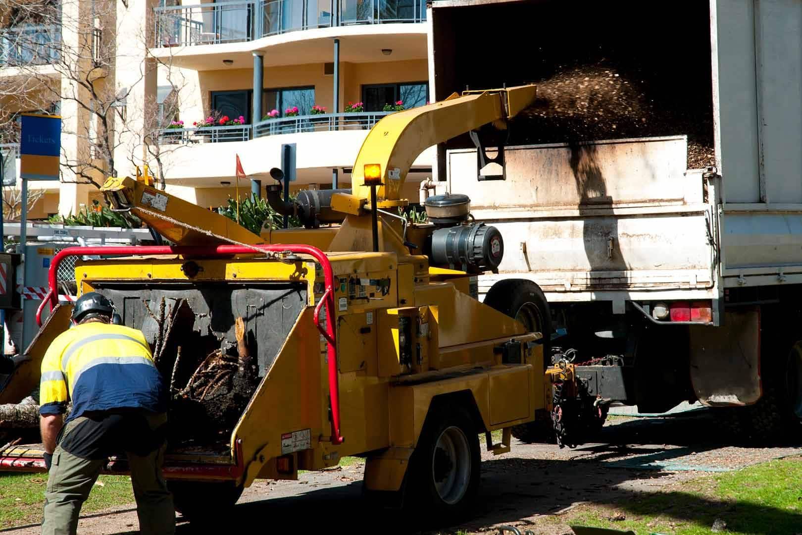 A Man is Working on a Tree Chipper Next to a Truck — Branch Manager Tree Services Coolum Beach In Caboolture, QLD