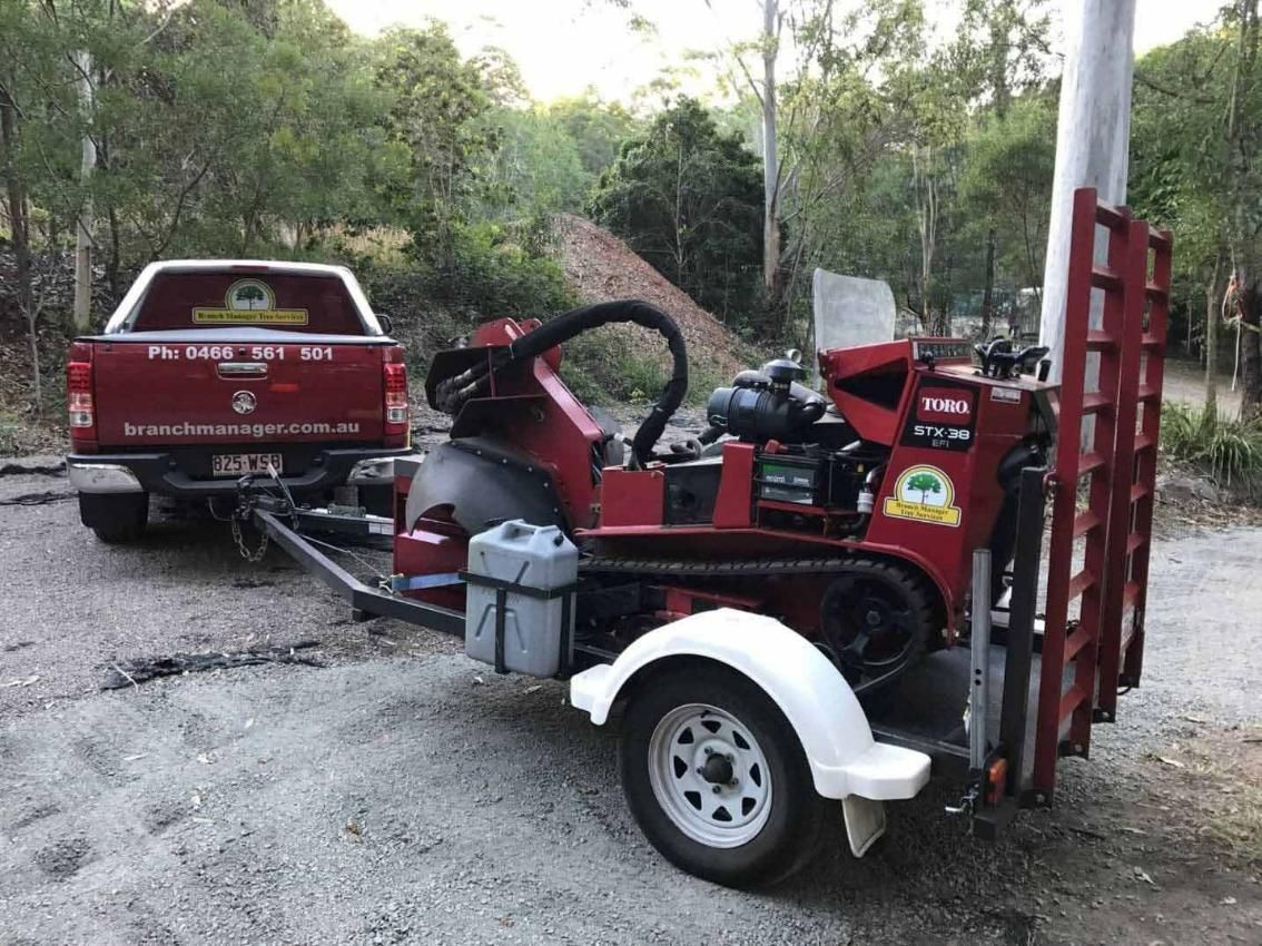 A Red Truck Is Towing A Red Machine On A Trailer — Branch Manager Tree Services Coolum Beach In Caboolture, QLD