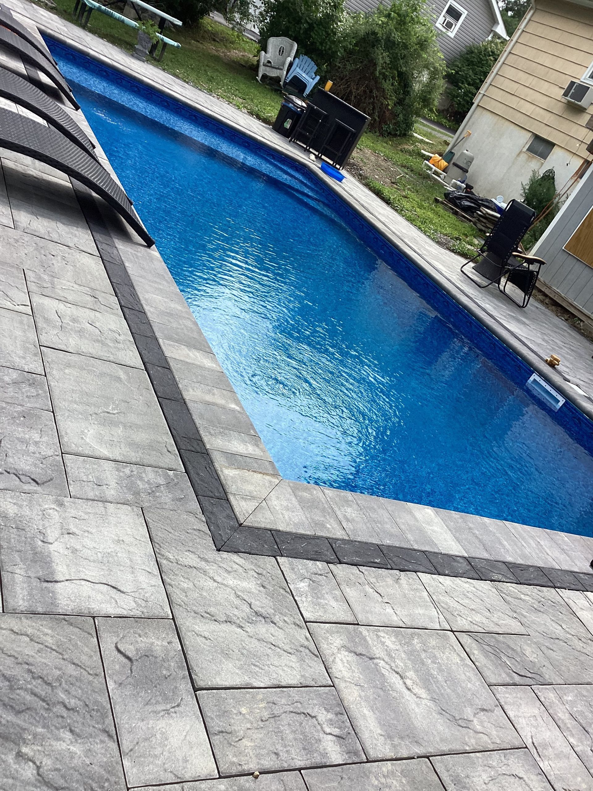 Rectangular pool with blue water, surrounded by gray pavers and a dark border.