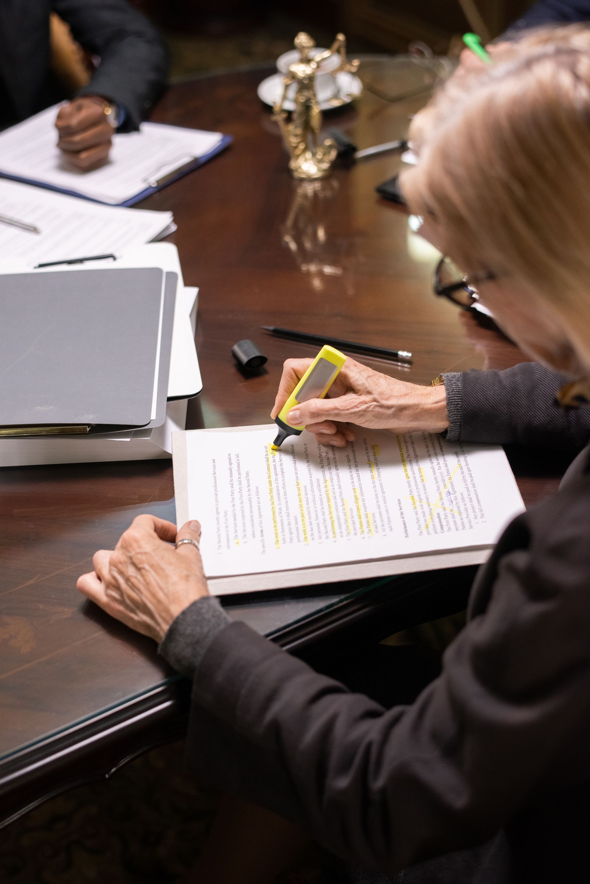 Person highlighting text on a document at a conference table, using a yellow highlighter.