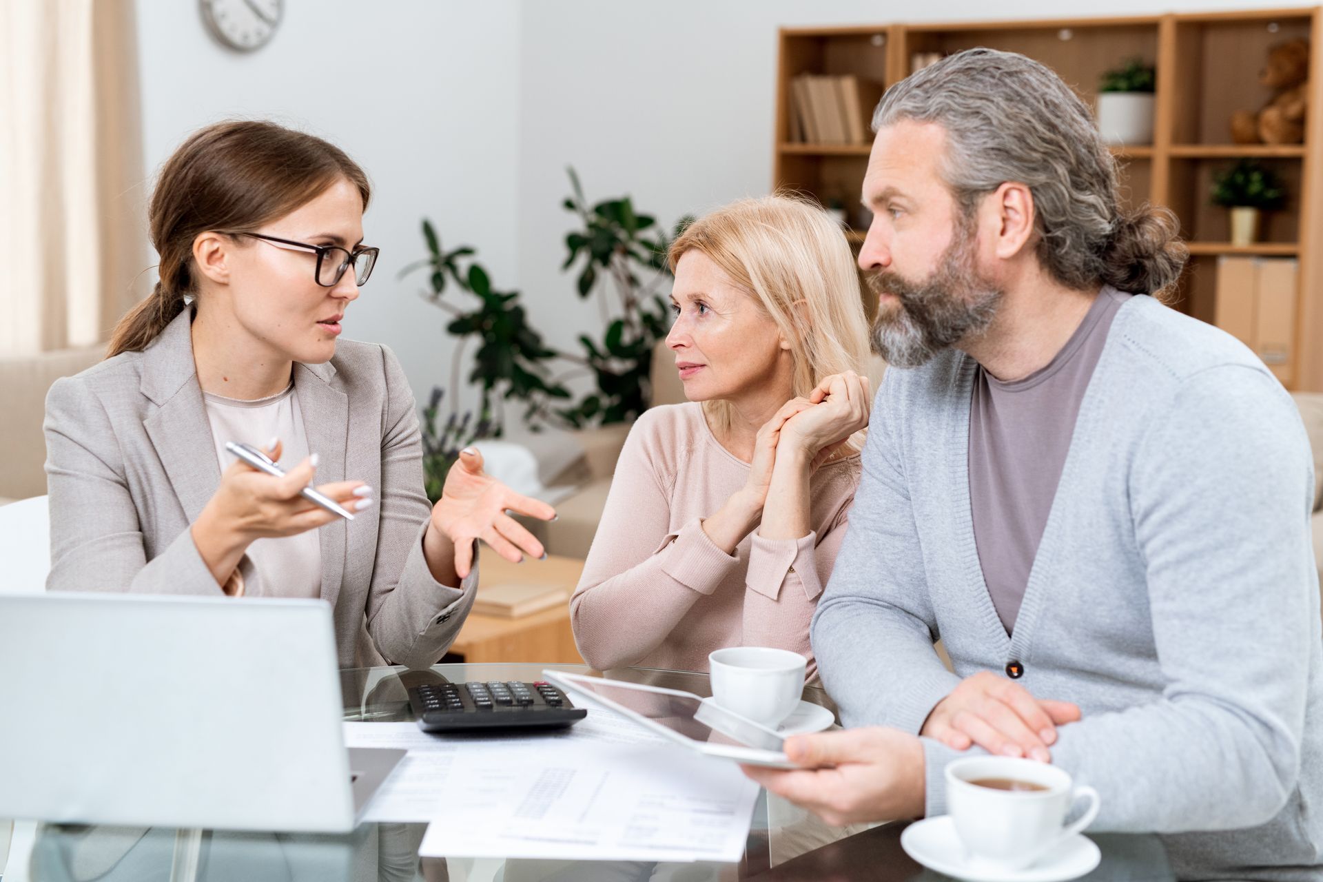Financial advisor speaking with a couple at a table, discussing documents.