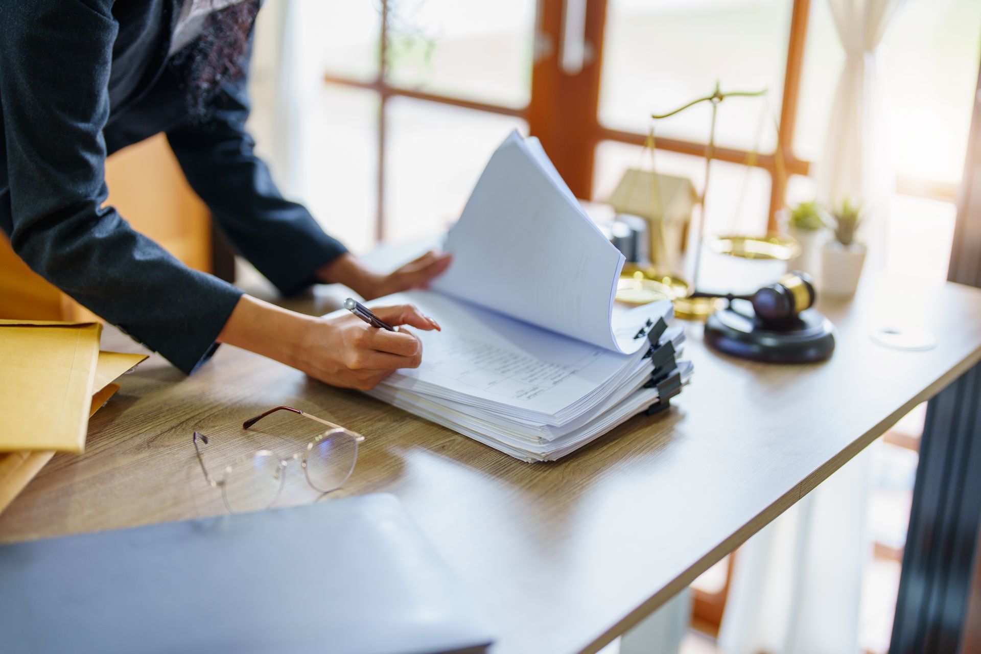 Person reviewing documents on a desk with a gavel and scales of justice.