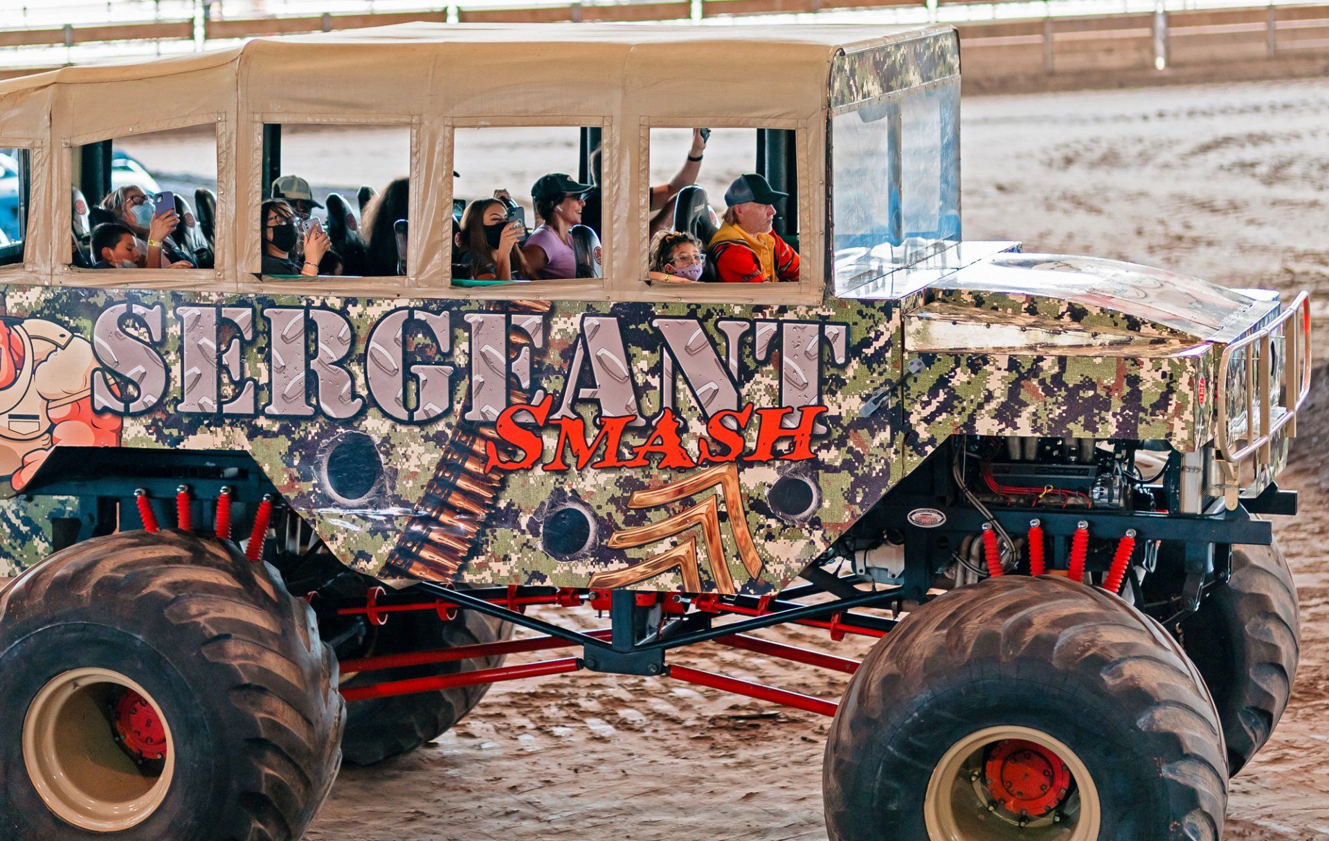 Sergeant Smash monster truck with camo and passengers waving from a boxy cabin.