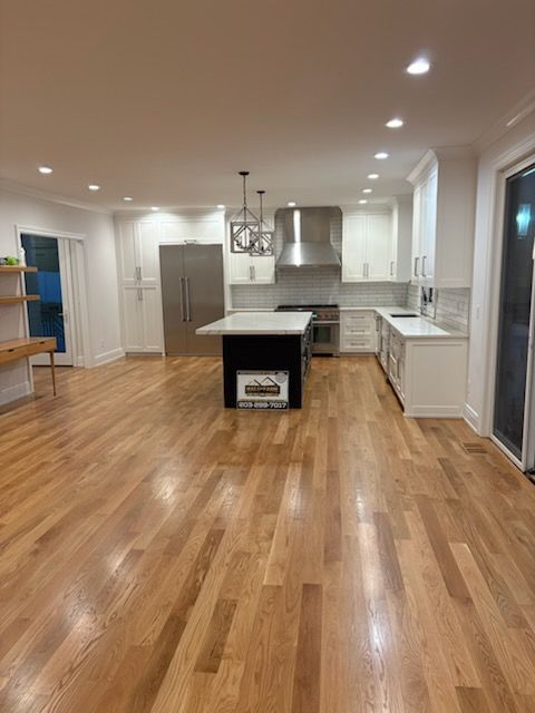 Spacious, modern kitchen with white cabinets, stainless steel appliances, and hardwood floors.