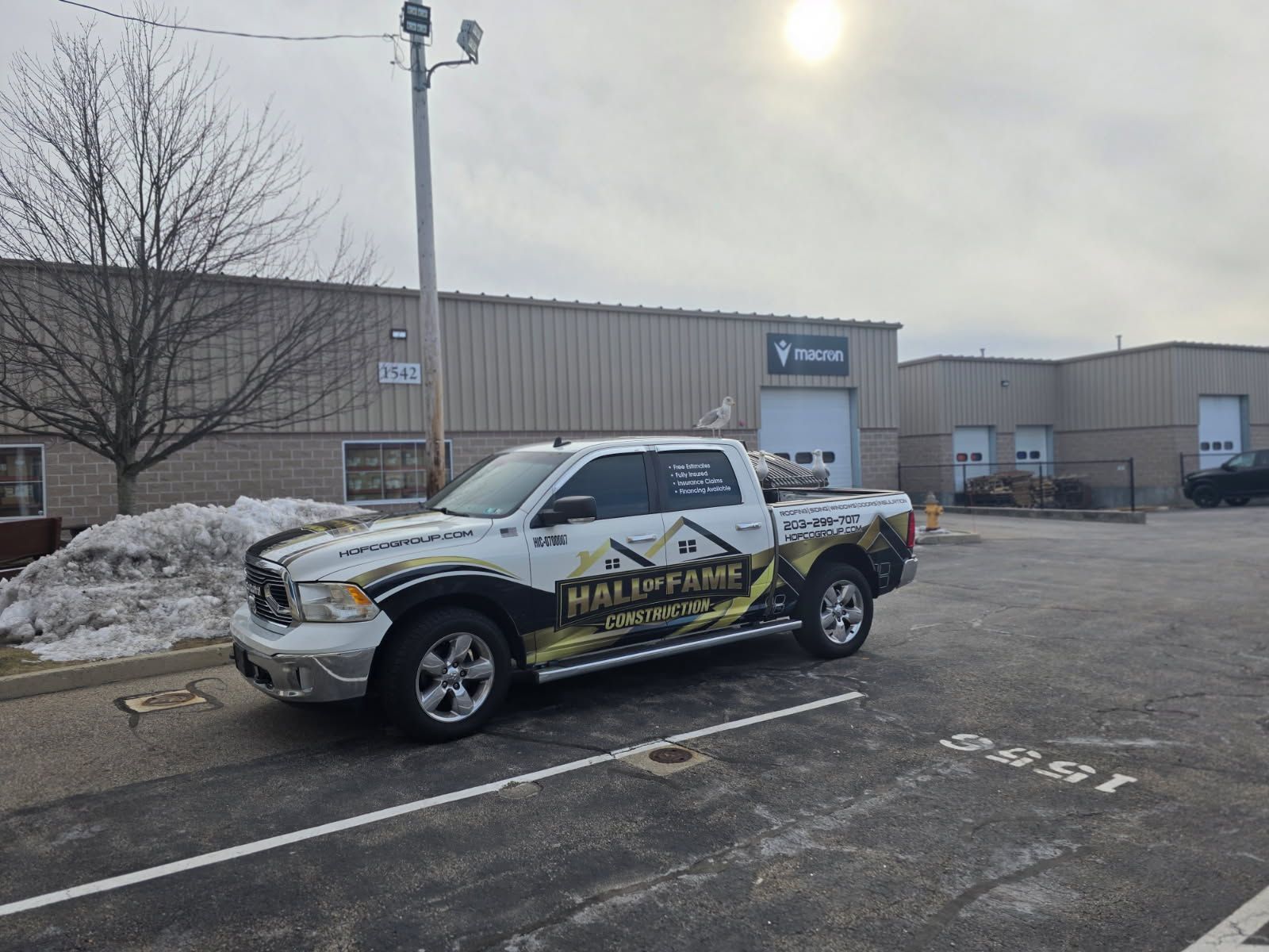 A white truck is parked in a parking lot in front of a building.