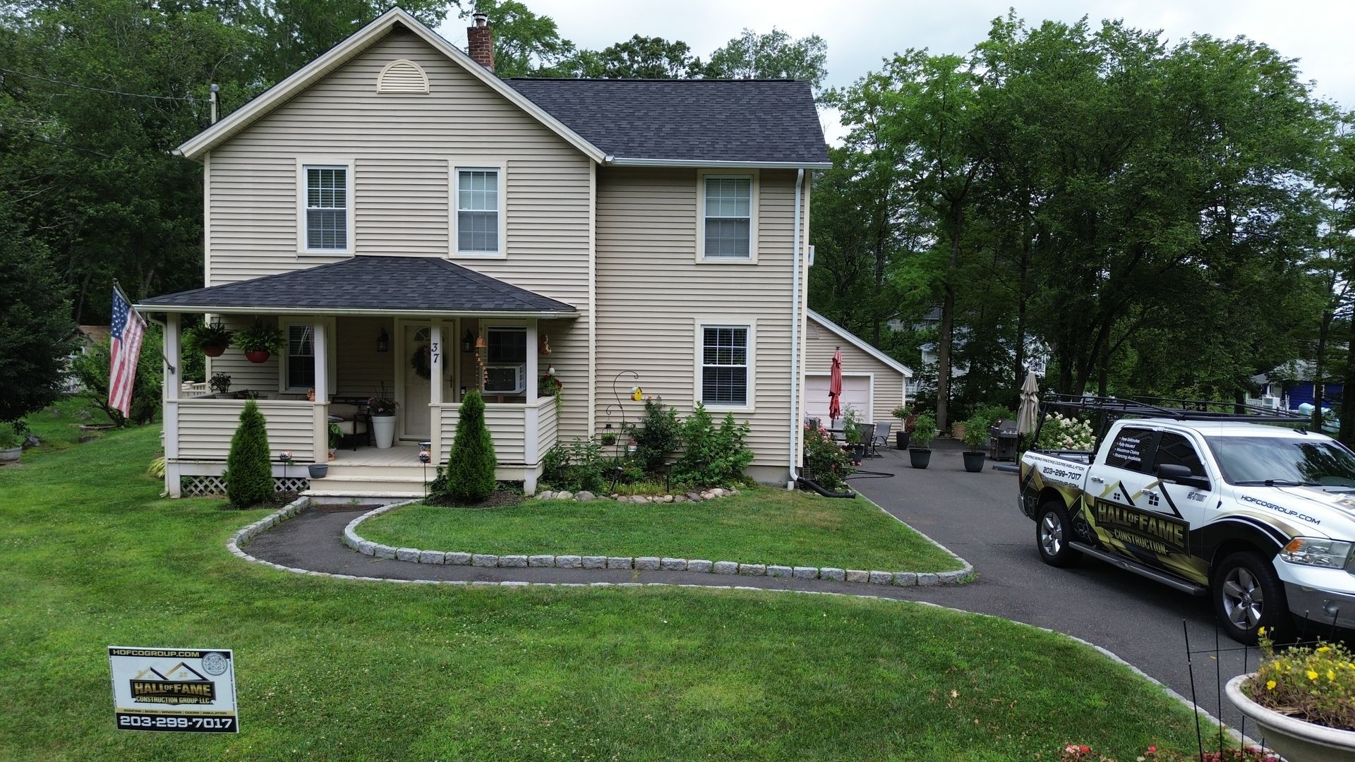 Two-story beige house with a front porch, curved walkway, and a white pickup truck parked in the driveway.