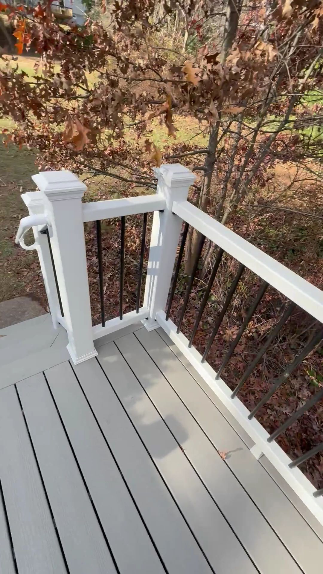 White porch deck with railings overlooking autumn trees and leaves below