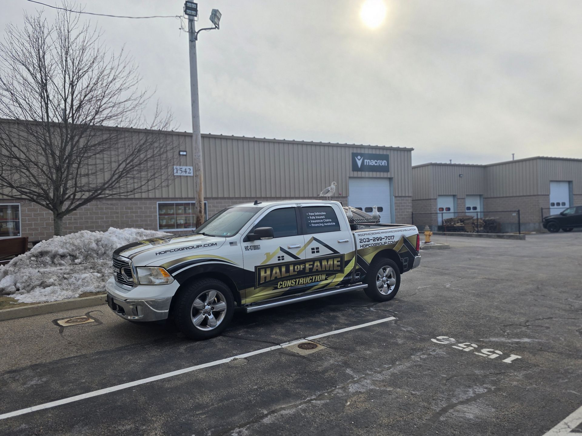 Pickup truck with yellow-black graphics parked outside a warehouse in a snowy lot