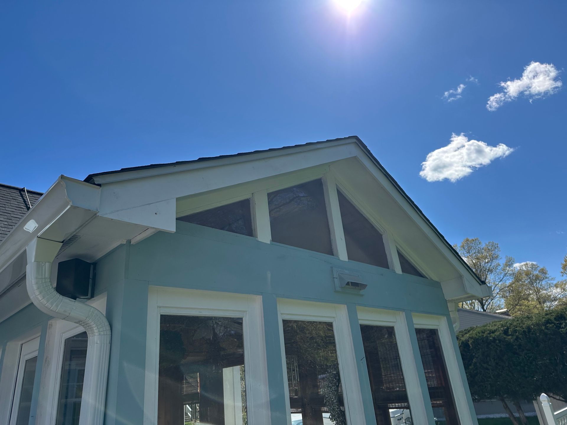 Blue house exterior with white trim and large windows under a bright sunny sky
