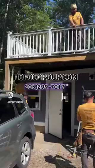 Two workers outside a Hof Door Up storefront, one on the roof and one at the entrance near a parked SUV.