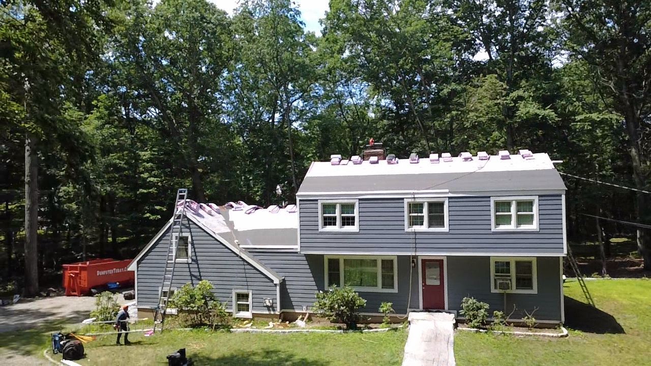 Two-story gray house with white trim and front walkway in a wooded yard
