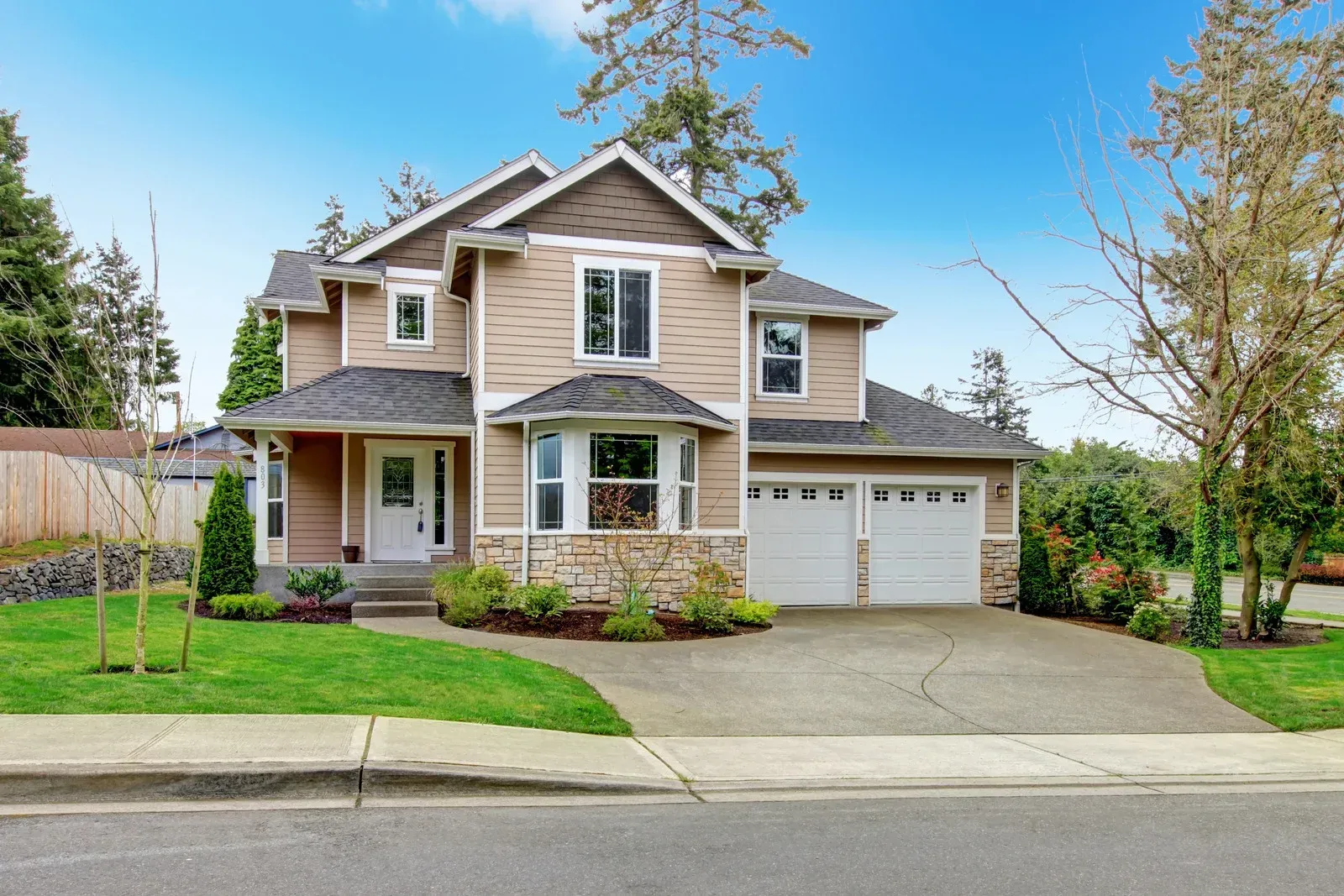 A large house with a large driveway is sitting on the side of the road.