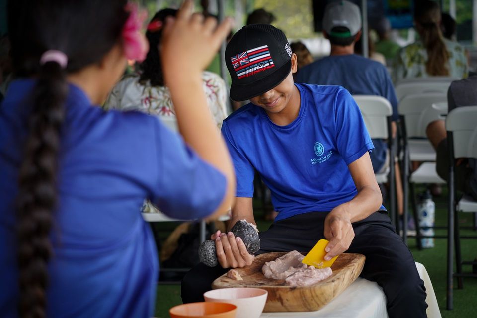 People in blue shirts shaping clay at pottery wheels in a workshop