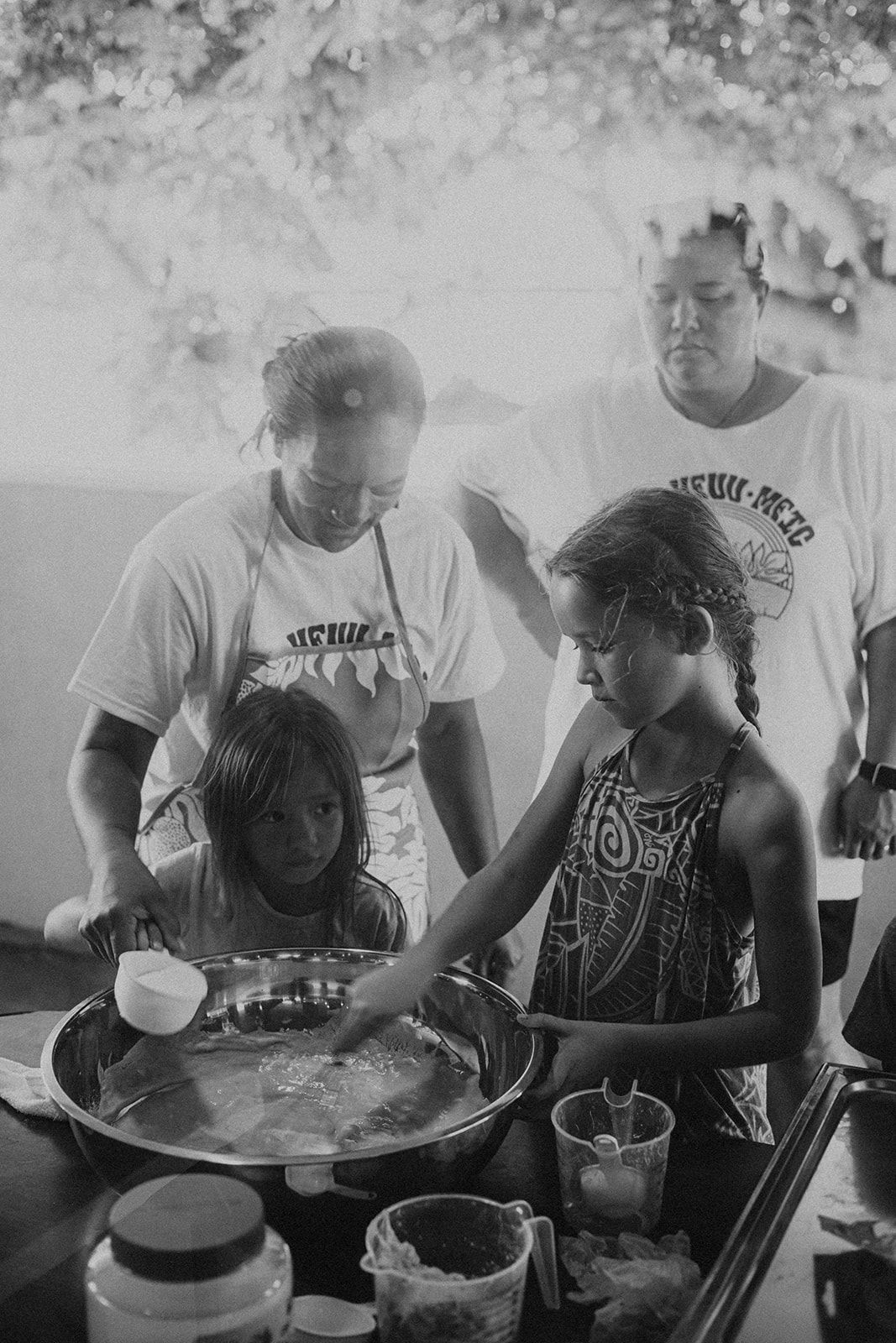 Children preparing food together outdoors around a table with bowls and utensils